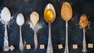 Different Kinds of Sugar in the Spoons, such as coconut sugar, pure cane sugar, icing sugar, agave syrup, dark brown soft sugar, golden caster sugar, demerara cubes